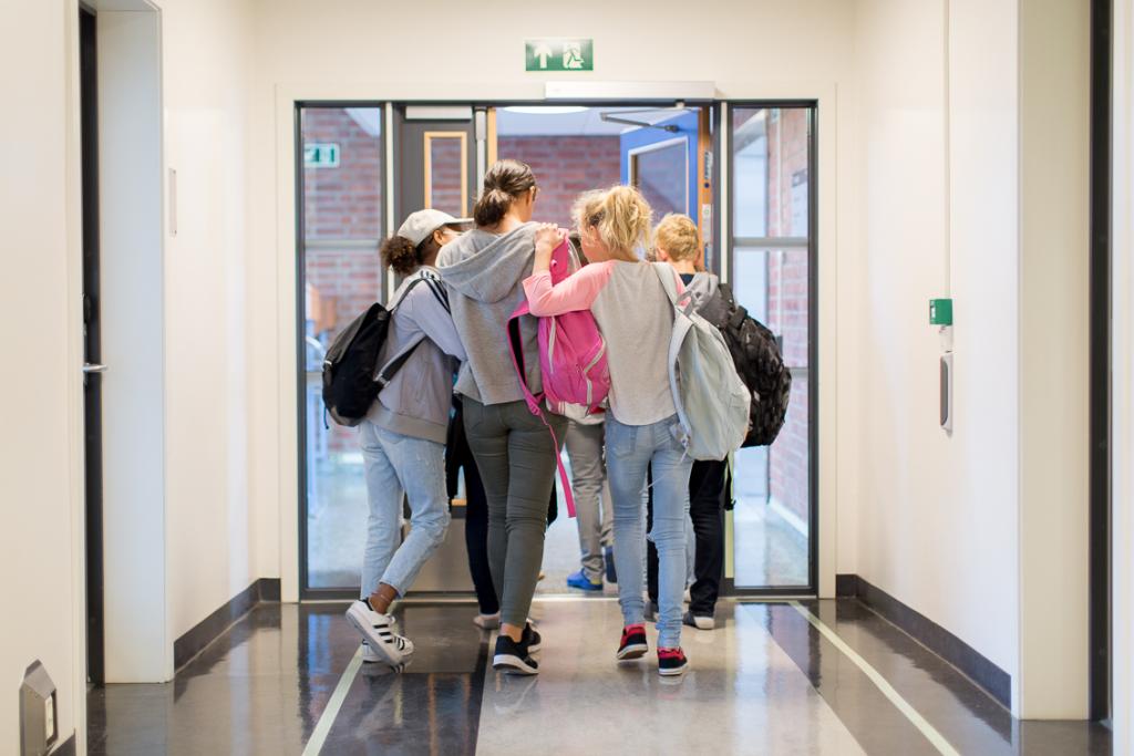 Bildet viser ungdomsskoleelever som går ut en dør