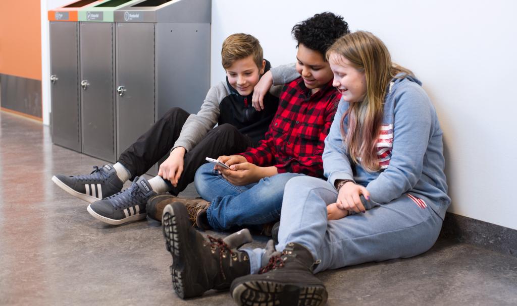 Tre ungdommer ser på en mobiltelefon