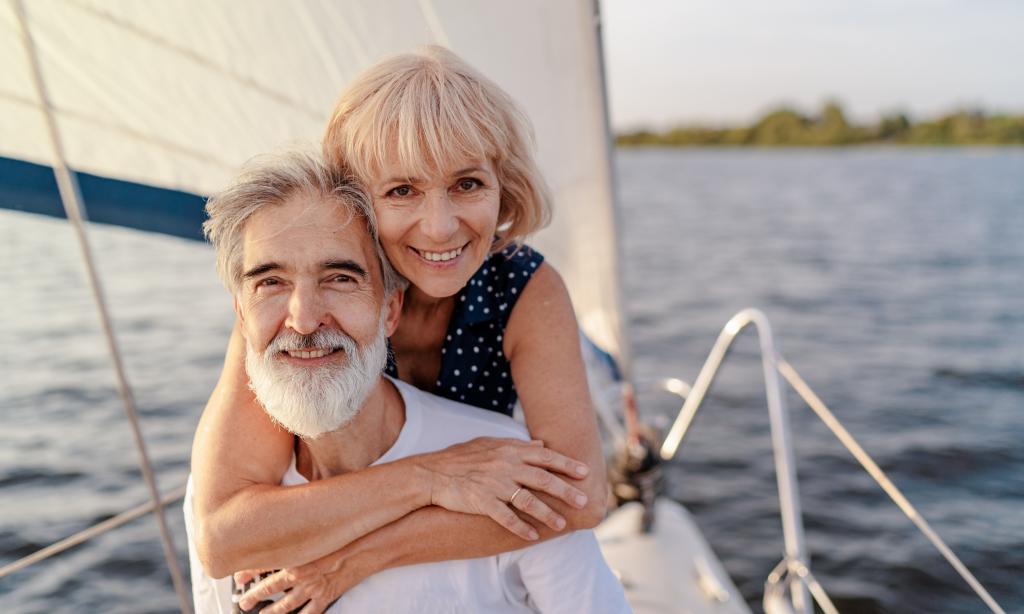 To smilende eldre personer på seilbåt