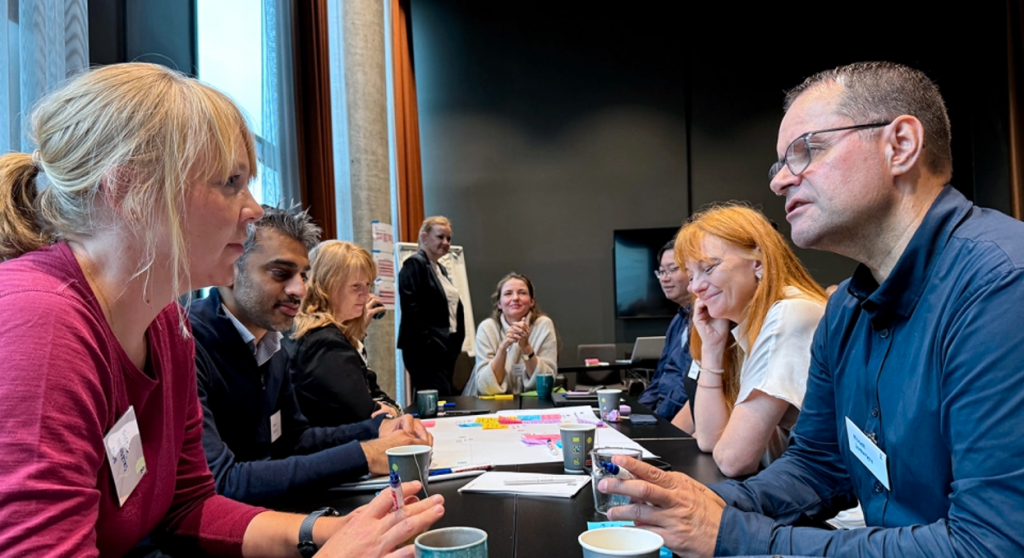 Bilde som viser den tverrfaglige dialogen og samarbeidet mellom Skatteetaten, NVE-RME, Statnett og Digdir i prosjektet. Bildet viser et nærbilde av representantene fra de ulike etatene hvor de sitter og diskuterer mellom seg.