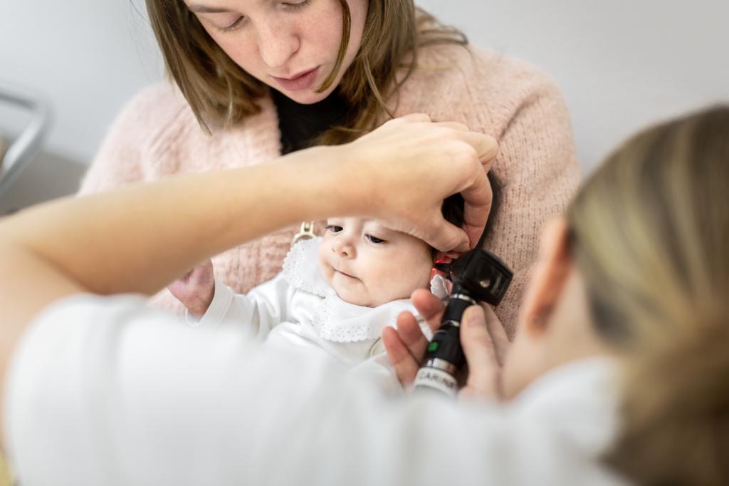 En baby i mors fang blir undersøkt av helsepersonell