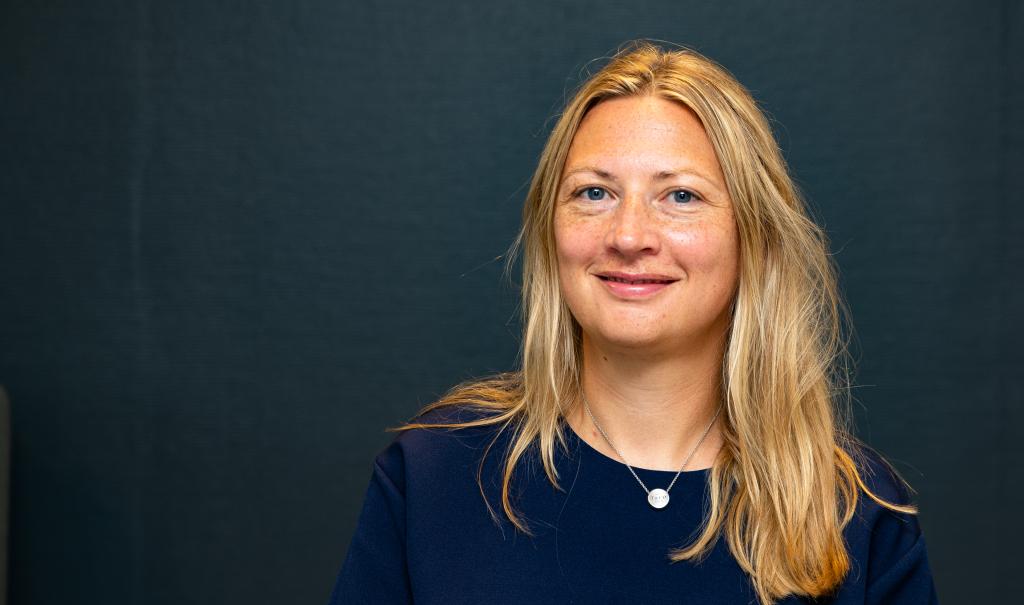 Foto av kvinne med lyst langt hår. Hun smiler og ser i kamera