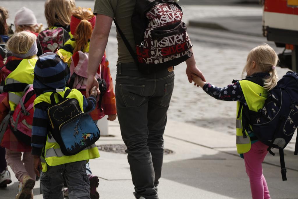 Bilde av voksen som holder barn i hånden på vei til skole