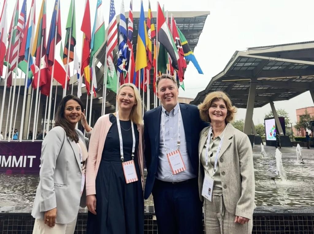 Ansatte fra Digdir utenfor AI Impact Summit i India 2026. Flagg i bakgrunnen. 